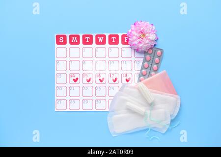 Calendrier menstruel avec produits féminins sur fond couleur Banque D'Images