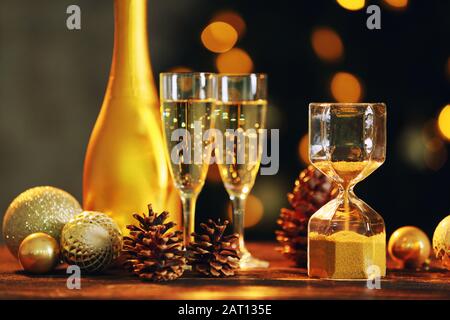 HourGlass avec décor de Noël et champagne à la table contre les lumières défocused Banque D'Images