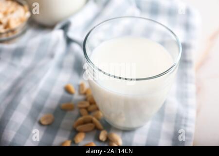 Verre de savoureux lait d'arachide sur table blanche Banque D'Images