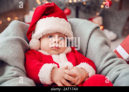 Joli petit bébé en costume de Père Noël à la maison Banque D'Images