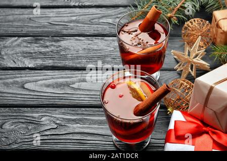 Verres de délicieux vin chaud, boîtes cadeaux de Noël et décor sur table Banque D'Images