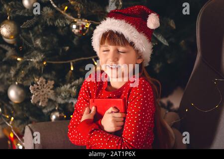 Jolie petite fille qui fait un souhait le soir de Noël à la maison Banque D'Images