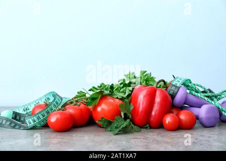 Différents aliments sains avec ruban de mesure et équipement sportif sur la table. Concept de régime alimentaire Banque D'Images