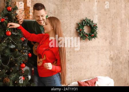 Heureux couple decorating Christmas Tree at home Banque D'Images