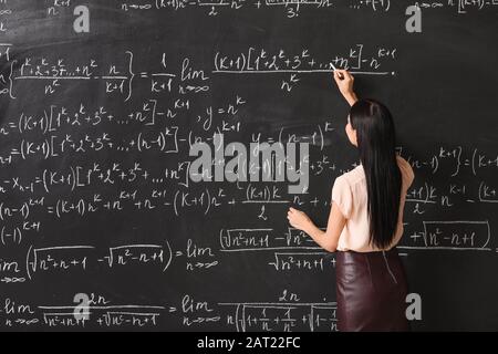 Professeur de femme écrivant sur le tableau noir en classe Banque D'Images