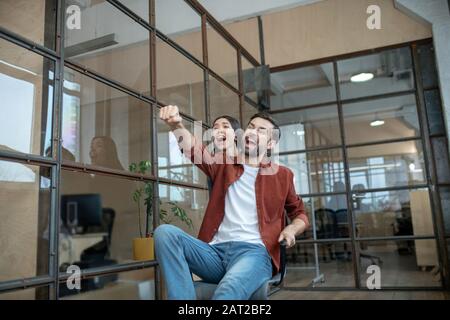 Un jeune couple s'amuse dans le couloir du bureau Banque D'Images