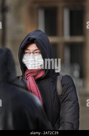 Masque de visage porté par un touriste chinois à l'extérieur de l'université de Gonville et Caius, Cambridge, Angleterre, le 30 janvier 2020, pour empêcher de attraper la grippe de coronavirus. Banque D'Images