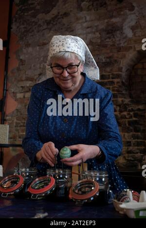 28 janvier 2020, Brandenburg, Lübbenau: Barbara Fix détient un œuf de Pâques décoré avec art dans ses mains. Elle porte la robe de travail traditionnelle des Sorbs/Wends. La fixité décorera jusqu'à 300 œufs de poule blanche par an selon leurs propres spécifications, en utilisant la technique traditionnelle de batik de cire ou la technique de bossy. Bien que Pâques ne soit célébrée qu'en avril, elle produit déjà les oeufs sorbiens afin qu'ils puissent être vendus dans des foires à Lusace peu avant Pâques. Photo : Stephan Schulz/dpa-Zentralbild/ZB Banque D'Images