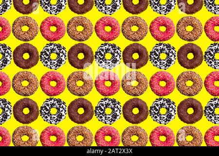 Motif de beignets roses et chocolat sur fond jaune vif vue de dessus, fond de beignets savoureux, papier peint sucré coloré dessert Banque D'Images