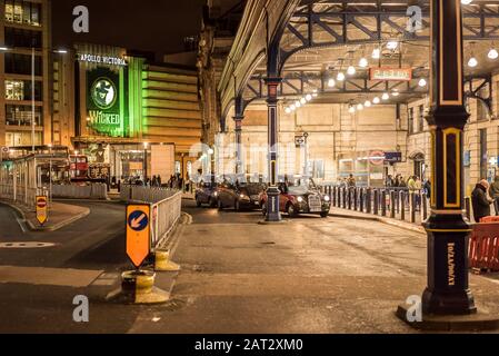 Scène urbaine à l'extérieur de l'entrée principale de la gare Victoria de Londres la nuit. Vue sur la file d'attente des taxis londoniens et la musique de scène Wicked à Apollo Victoria. Banque D'Images