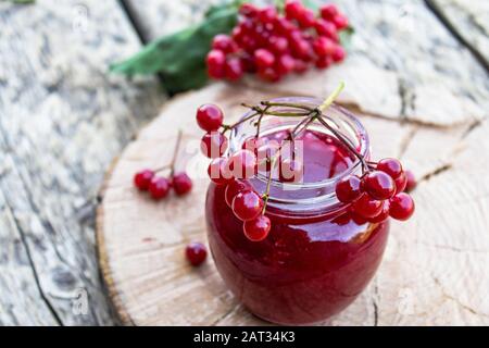 Bocal en verre de confiture de viburnum maison avec baies de viburnum fraîches sur une table en bois. Source de vitamines naturelles. Utilisé en médecine populaire. Récolte d'automne. Banque D'Images