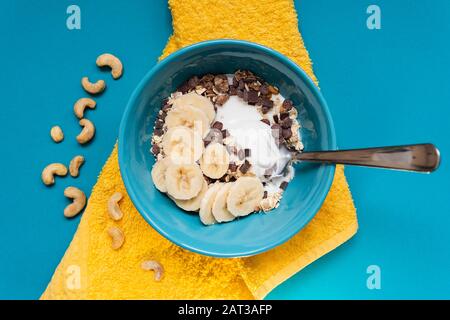 Bol de céréales saines avec yaourt et bananes sur un tableau bleu Banque D'Images