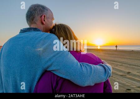 Un couple d'âge moyen se réunit pour regarder le lever du soleil sur la plage, Gran Canaria. Banque D'Images
