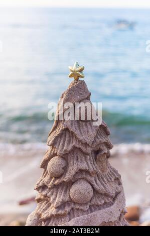 Gros plan vertical d'un arbre de Noël en forme de sable sur la plage Banque D'Images