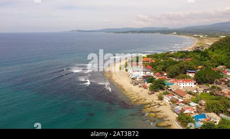 Ville côtière avec un surfer beach. San Juan, la région, les Philippines. Plage avec des hôtels pour touristes, vue aérienne. Billet d'été et vacances. Banque D'Images