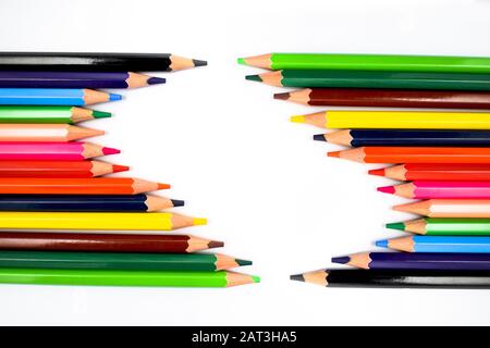 Gros plan photo de deux rangées différentes de crayons de couleur en bois face l'une de l'autre dans une formation de vague Banque D'Images