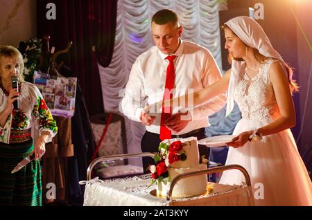 Couple de mariage mignon en vêtements traditionnels ukrainiens assis sur le banc dans la ville et passer du temps ensemble. Banque D'Images