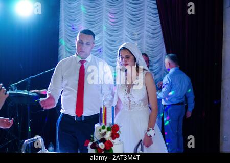 Couple de mariage mignon en vêtements traditionnels ukrainiens assis sur le banc dans la ville et passer du temps ensemble. Banque D'Images