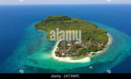 Himokilan Island, l'île de Leyte, aux Philippines. Île tropicale avec un village et d'une plage de sable blanc. L'eau turquoise et des récifs coralliens autour de l'île. Maison de vacances d'été. Banque D'Images