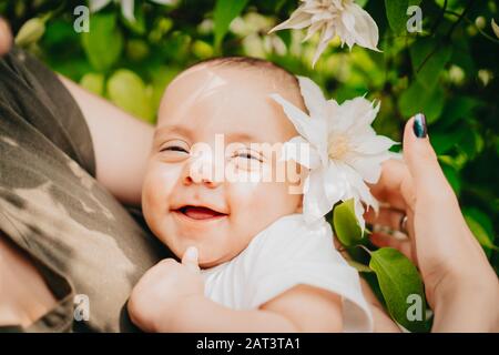 Beau portrait de petit garçon de bébé sur fond de buisson de fleurs. Enfant en fleur de printemps. Joli fils nouveau-né souriant. Banque D'Images