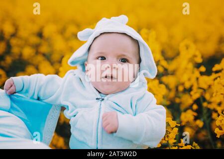 Mignon petit garçon portrait dans le champ de colza de canola sur fond de fleurs jaunes, famille, fils, enfant tout-petit concept. Banque D'Images
