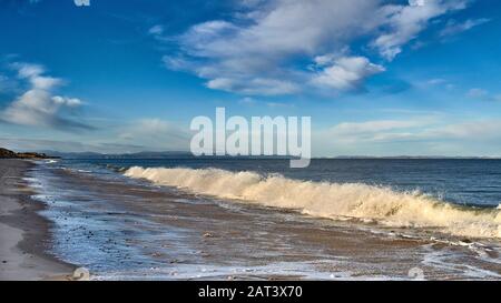 FINDHORN BEACH MORAY SCOTLAND SANDY BEACH BLUE SKY SEA ET UNE GRANDE VAGUE DE BRISEURS ET DE SURF BLANC Banque D'Images