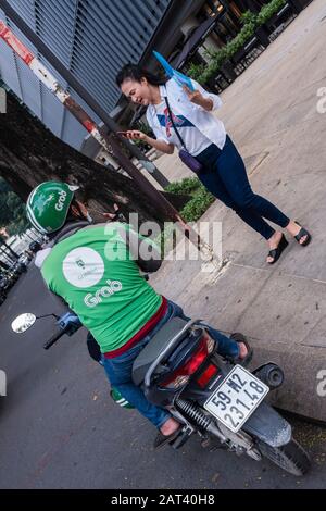 Les jeunes femmes utilisant Grab taxi via l'application mobile, Ho Chi Minh Ville, Vietnam Banque D'Images