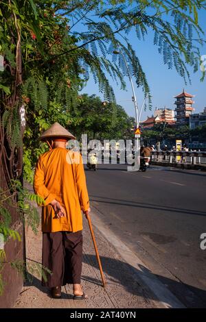 Homme âgé en utilisant un bâton de marche pour se promener le long de la rue, Ho Chi Minh Ville, Vietnam Banque D'Images