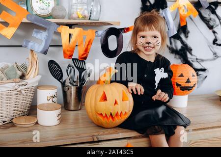 Petite fille assise à côté de la citrouille et montrant un geste effrayant. - concept d'Halloween Banque D'Images