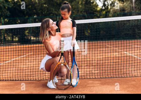 La mère affectueuse admire sa fille sur le court de tennis Banque D'Images