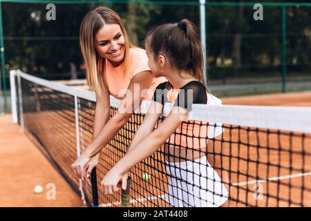 Belle mère et fille sur le court de tennis en admirant parler de jouer au tennis Banque D'Images