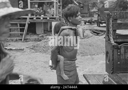 Photo Reportage Palembangs homme indonésien avec enfant au dos. L'enfant a un look. Les jeeps sont affichés. Date : Janvier 1947 Lieu : Indonésie, Antilles Néerlandaises De L'Est, Palembangs, Sumatra Banque D'Images