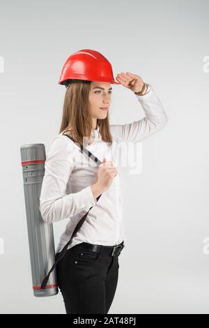 Femme architecte se tient avec un tube derrière son dos touche casque orange sur sa tête. - image verticale Banque D'Images