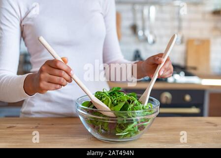 Gros plan les mains des femmes pendant la cuisson d'une nourriture saine, agite avec des cuillères une salade Banque D'Images