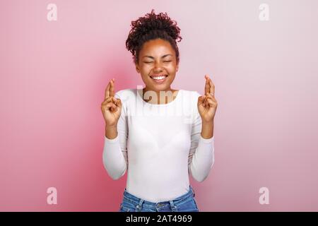 Mignonne femme mulatto croisant ses doigts et souhaitant bonne chance - image Banque D'Images