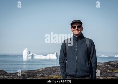 Jeune homme traveler'debout devant d'iceberg. Vue vers à Ilulissat Icefjord. Les icebergs du glacier Kangia au Groenland de natation avec b Banque D'Images