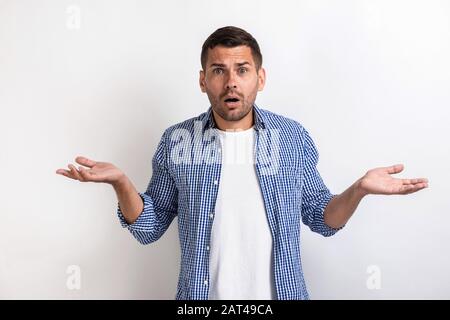 Beau homme étonné debout avec un look surprise et des mains séparées en studio Banque D'Images