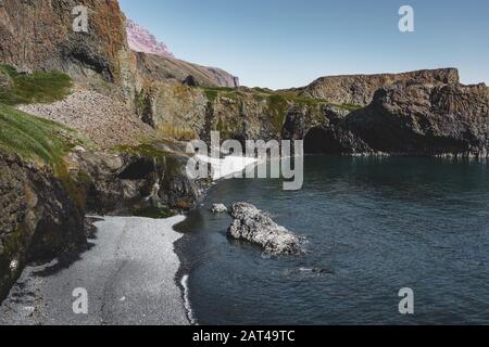 Plage arctique avec petite chute d'eau au Groenland. Près du petit village de Qeqertarsuaq, île Disko au Groenland. Ciel bleu avec océan et plantes vertes. P Banque D'Images