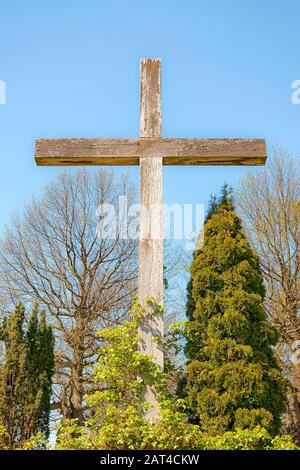 Une grande croix en bois sur fond d'arbres et de ciel bleu. Banque D'Images