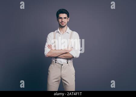 Photo de macho homme d'affaires bras croisé souriant charmant jeune fiable chef habillé formalwear blanc chemise beige suspenders spécifications pantalon isolé Banque D'Images