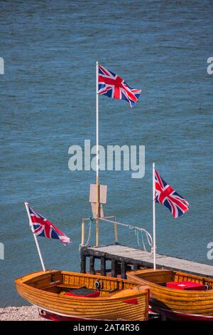 Louez des bateaux sur la plage de galets à Beer à Devon avec les drapeaux Union Jack. Banque D'Images