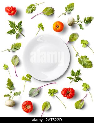 Vue de dessus de la plaque blanche isolée avec tomates et légumes verts Banque D'Images