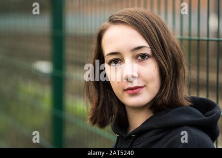 Headshot d'une jeune fille de 17 ans d'université avec un accrochage posant contre un mur rugueux Banque D'Images