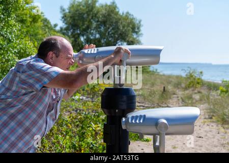 Homme Plus Âgé Regardant La Mer Par Le Télescope D'Observation De La Zone D'Observation Banque D'Images