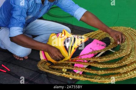 Artiste local travaillant sur un masque de visage traditionnel utilisé pour une danse folklorique indienne régionale à un tarif artisanal à Kolkata Banque D'Images