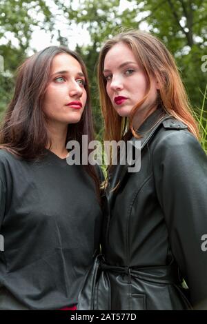 Portrait de deux jeunes femmes de race blanche et indienne se tenant côte à côte en regardant loin. Prise de vue moyenne. Banque D'Images