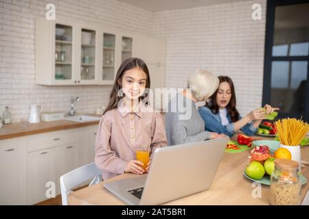 Fille avec jus et grand-mère de parler avec maman. Banque D'Images