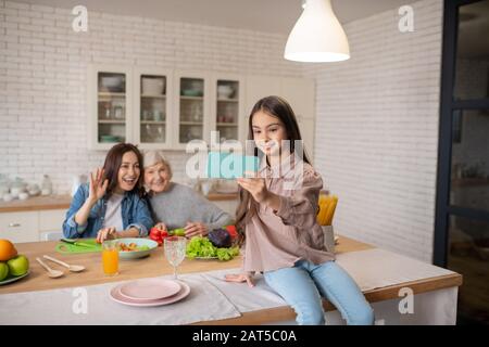 Fille prenant selfie avec maman et grand-mère dans la cuisine. Banque D'Images