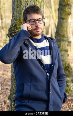 Homme sérieux, parler sur téléphone mobile dans un parc d'automne . Banque D'Images