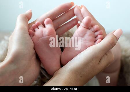 les jambes de bébé dans les mains de la mère Banque D'Images